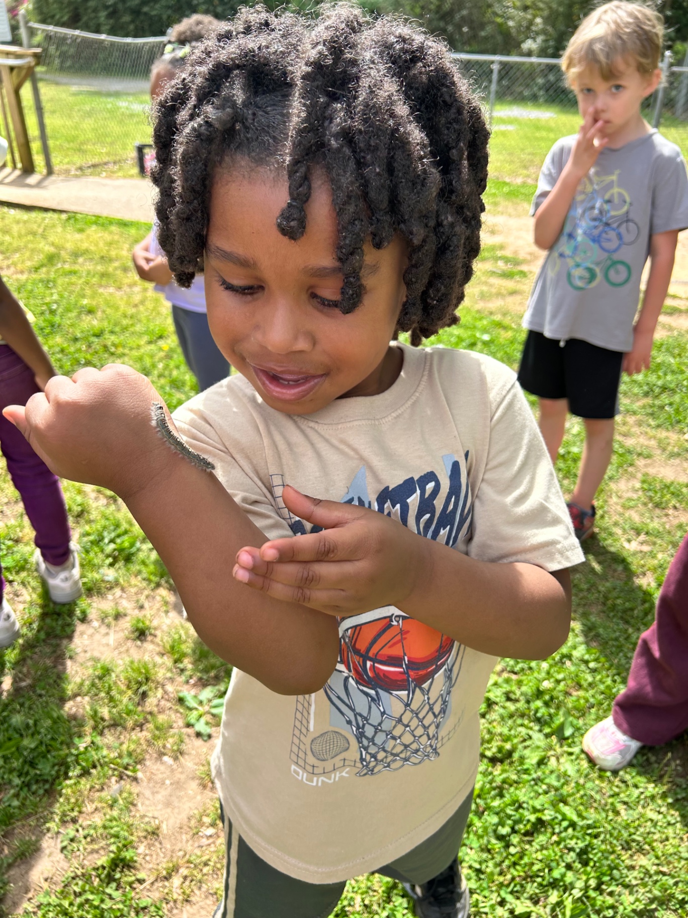 A child observing a caterpillar on their arm