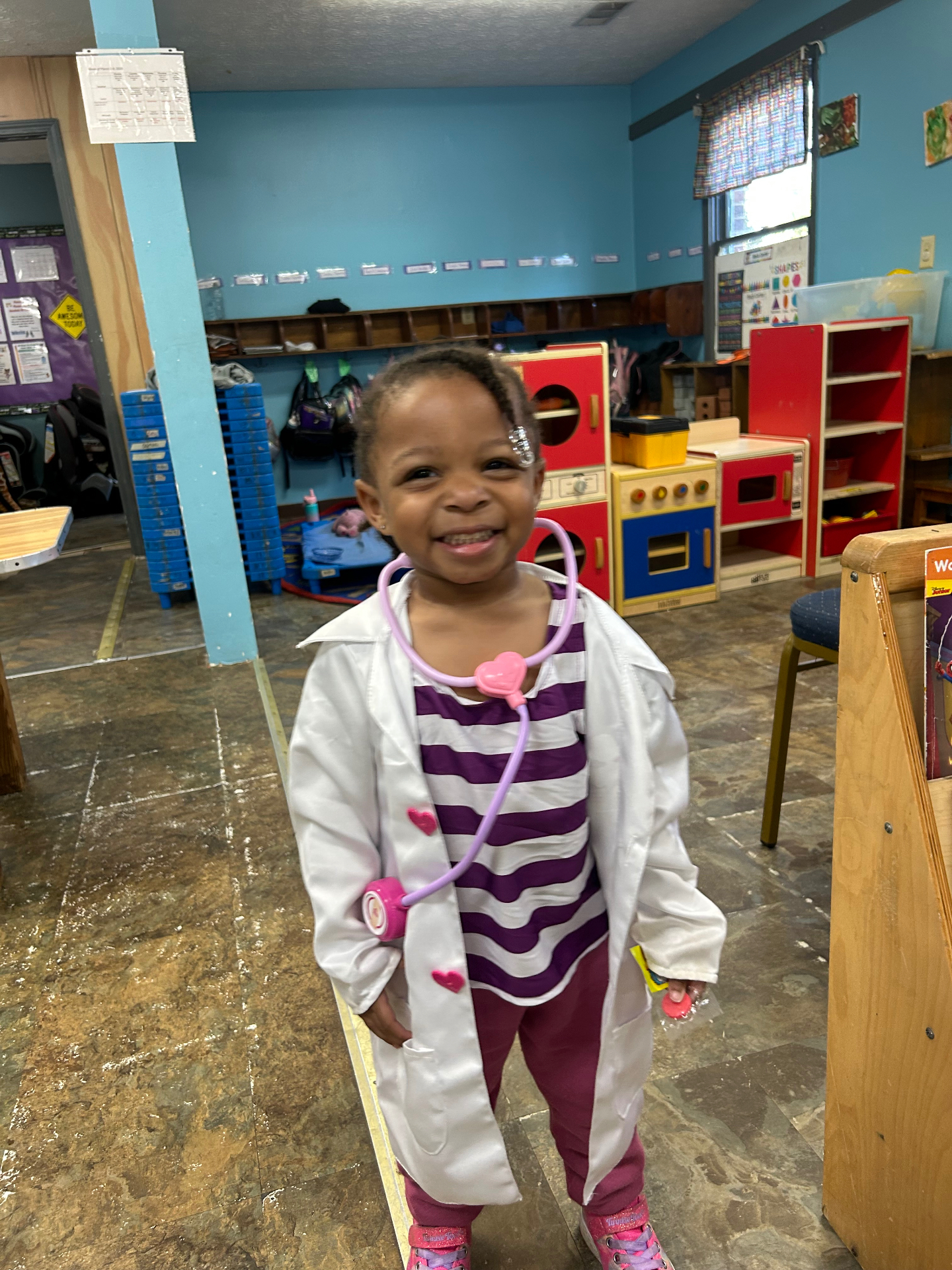 A smiling child playing doctor in the classroom