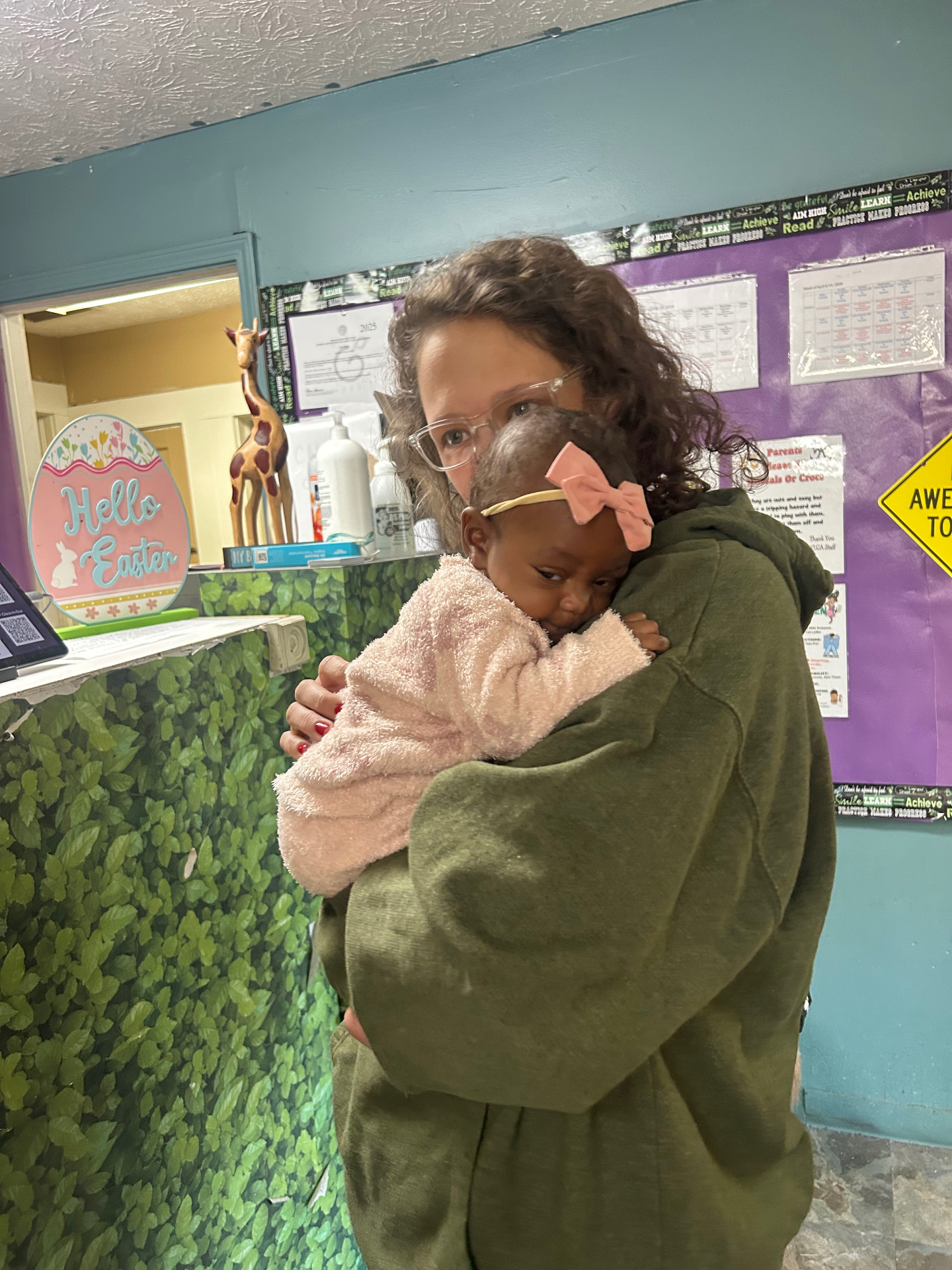 A teacher holding an infant in her arms